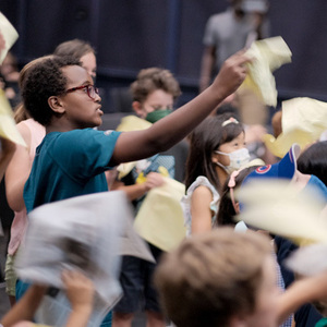 Children waving yellow papers in the air.