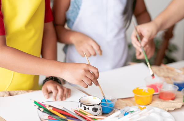 Children painting with colorful paints and brushes during an art class.